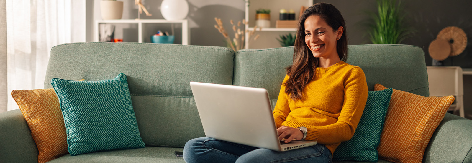 Women sitting on the couch working on a laptop computer.